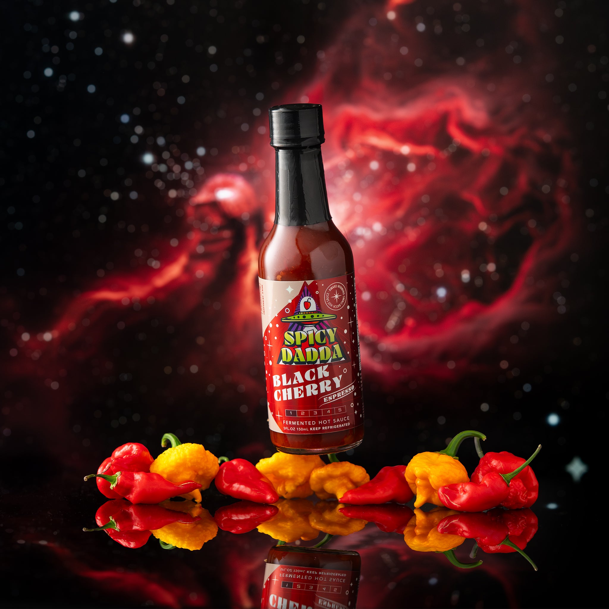 Spicy Dadda Black Cherry Espresso fermented hot sauce bottle surrounded by fresh dark cherries and espresso beans against a surreal cosmic space background.